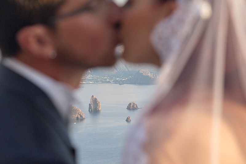 faraglioni lipari e vulcano sullo sfondo con sposi che si baciano