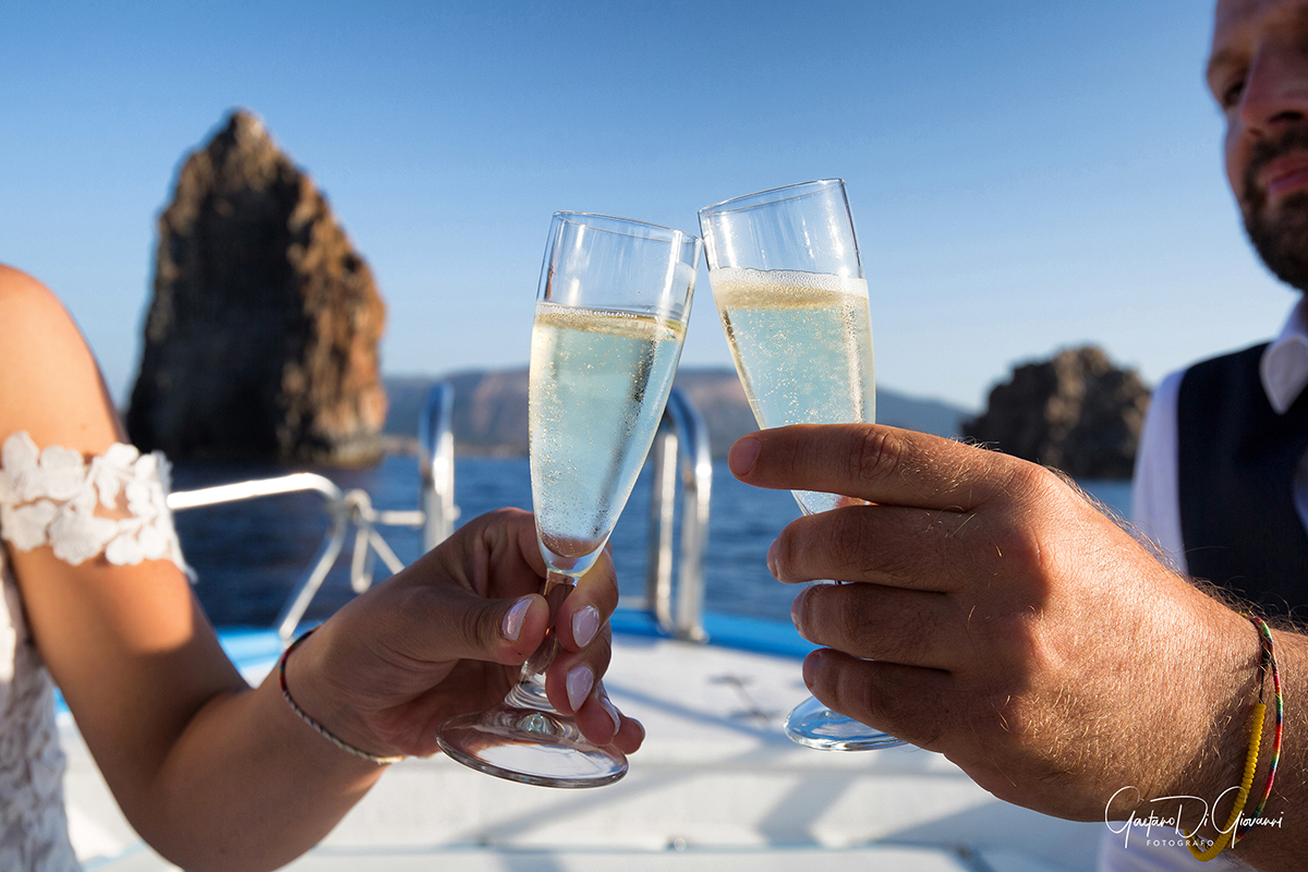 Scatto romantico di sposi in barca a Lipari, brindisi sul mare 