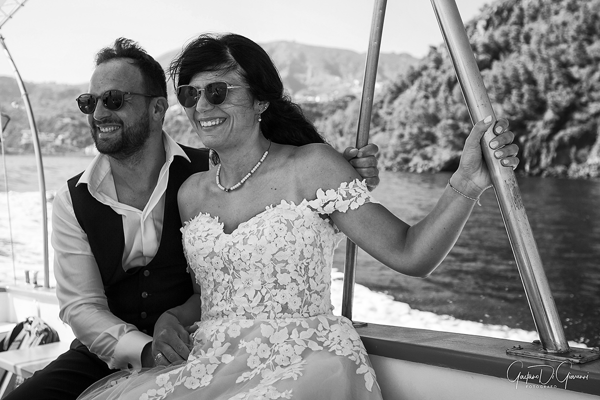 Scatto di matrimonio in barca a Lipari, sposi sorridenti mentre navigano nel mare delle Isole Eolie.