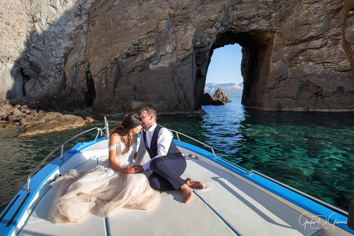 Sposi in barca a Lipari, scatto romantico durante il matrimonio con le Isole Eolie sullo sfondo.
