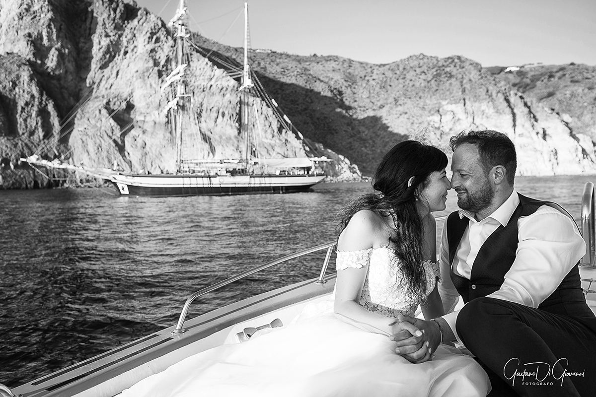 Coppia di sposi in barca a Lipari, con il mare cristallino delle Isole Eolie sullo sfondo."