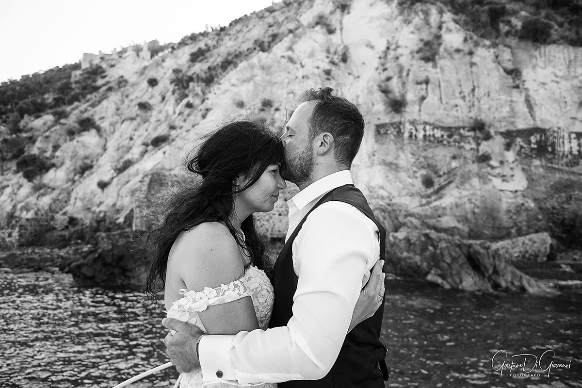 Matrimonio in barca a Lipari: coppia di sposi abbracciata con il mare cristallino e le Isole Eolie